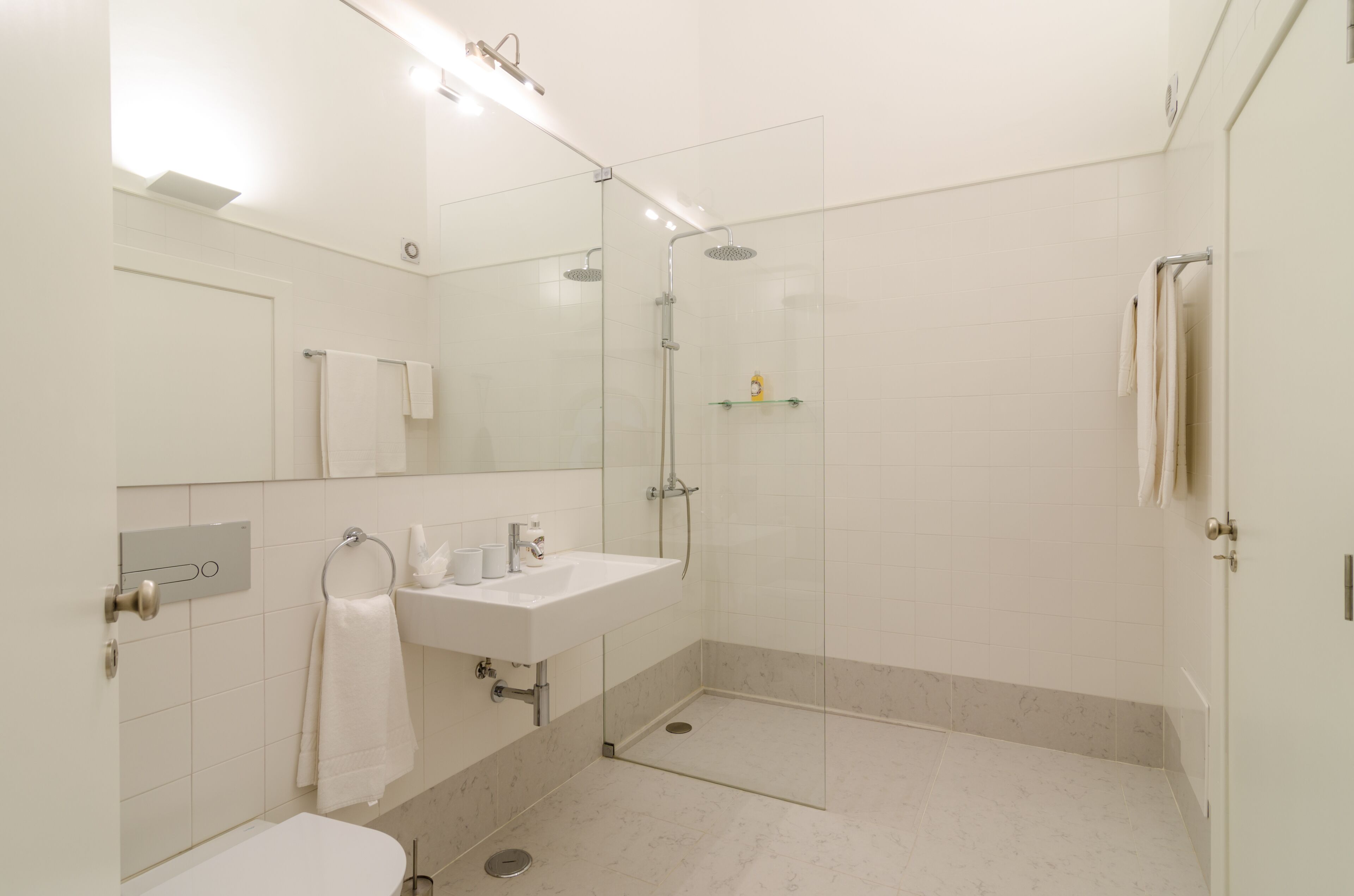 A modern bathroom with a glass-enclosed shower, a white sink, and a toilet.