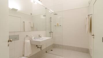 A modern bathroom with a glass-enclosed shower, a white sink, and a toilet.