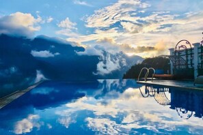 A clear pool with a reflection of the sky and clouds, a metal structure on the right, and a calm water surface. - Pistachio Hotel Sapa (Sa Pa)