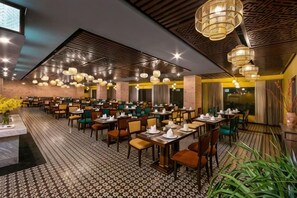 A spacious restaurant with multiple dining tables and chairs, high ceilings with hanging lights, and a patterned floor. - Pistachio Hotel Sapa (Sa Pa)