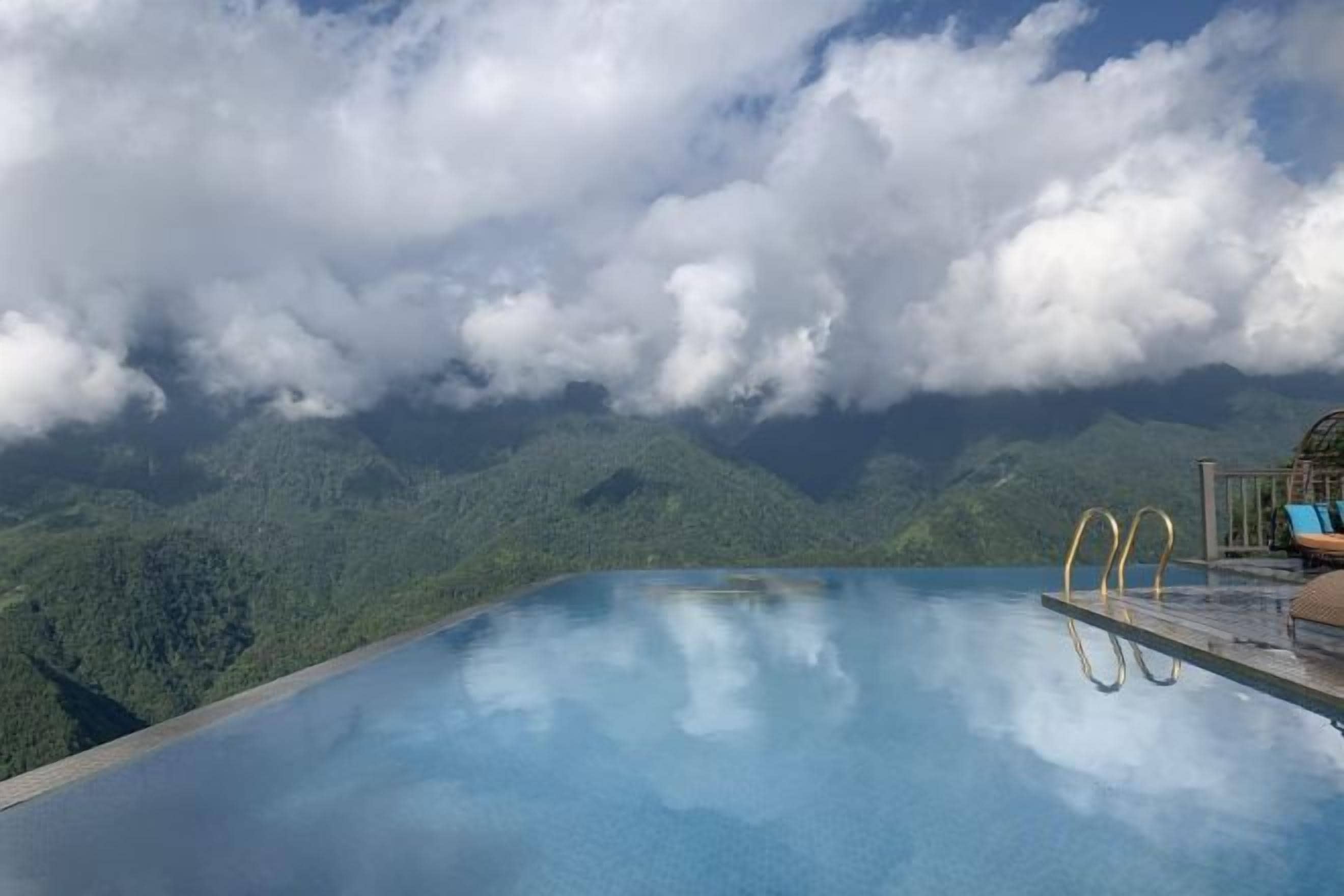 An infinity pool with a view of mountains and clouds.