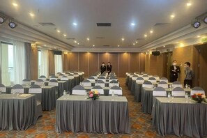 Un salón de conferencias con varias mesas, cada una con placas de identificación y vasos de agua.
