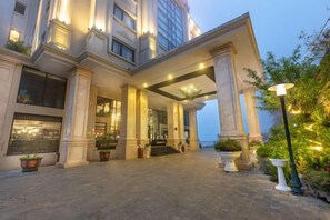 Een hotelgevel met een statig uiterlijk, grote kolommen en een goed verlichte entree.