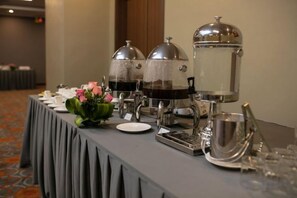 A buffet setup with multiple beverage dispensers, a floral centerpiece, and a variety of tableware. - Pistachio Hotel Sapa (Sa Pa)