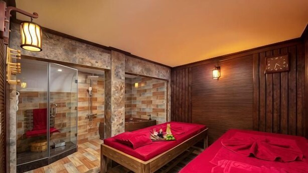 A room with a wooden floor, a glass shower enclosure, a wooden bench with red cushions, and a wooden wall with a clock. - Pistachio Hotel Sapa (Sa Pa)