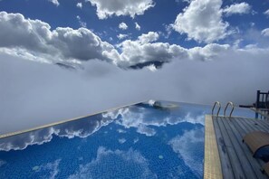 An infinity pool with a wooden deck and a clear view of the sky and clouds. - Pistachio Hotel Sapa (Sa Pa)