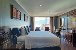 A hotel room with a large bed, a desk with a chair, and a view of the outdoors. - Pistachio Hotel Sapa (Sa Pa)