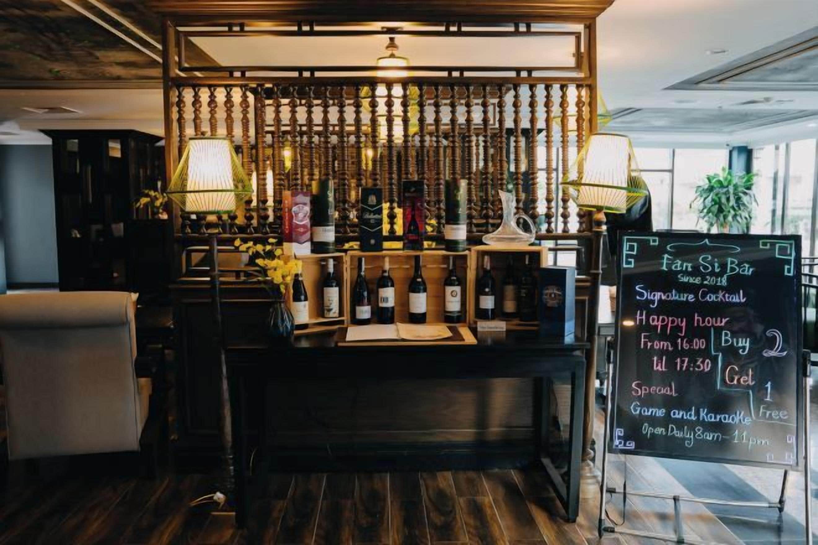 A bar area with a wooden counter, bottles, and a chalkboard menu.