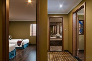 Ein Hotelzimmer mit Bett, einem Badezimmer mit Spiegel und einem Flur mit einem gemusterten Boden.