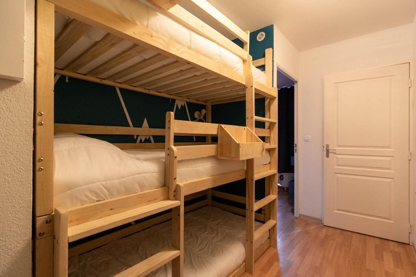 A bunk bed room with a door and a wall with a geometric pattern.