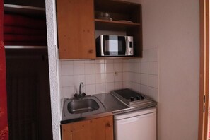 Uma cozinha compacta com pia de aço inoxidável, micro-ondas, fogão e lava-louças.