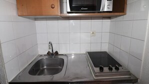 Una cucina compatta con un lavello doppio, un forno a microonde e una stufa.