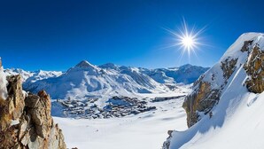 Paesaggio montano innevato con affioramenti rocciosi e un cielo azzurro limpido.