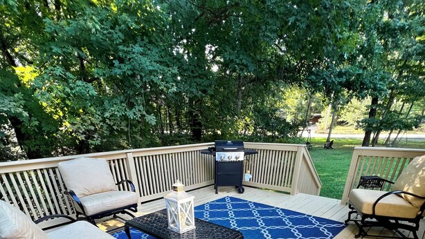 A wooden deck with outdoor furniture, including a sofa, chairs, and a small table. - Lake Life Getaway! (Winchester)