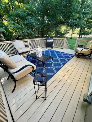 A wooden deck with outdoor furniture, including a sofa, chairs, and a small table. - Lake Life Getaway! (Winchester)