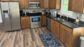 A modern kitchen with wooden cabinets, stainless steel appliances, a built-in oven, microwave, and refrigerator. - Lake Life Getaway! (Winchester)
