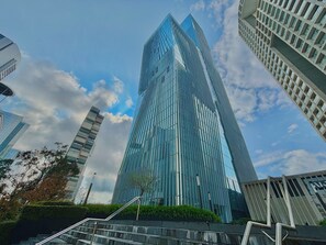 A modern skyscraper with a curved glass facade, surrounded by other high-rise buildings. - Park life Paradox Santa Fe (Mexico City)