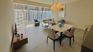 Un comedor moderno con una mesa de mármol, sillas y vistas a edificios de la ciudad a través de amplias ventanas.