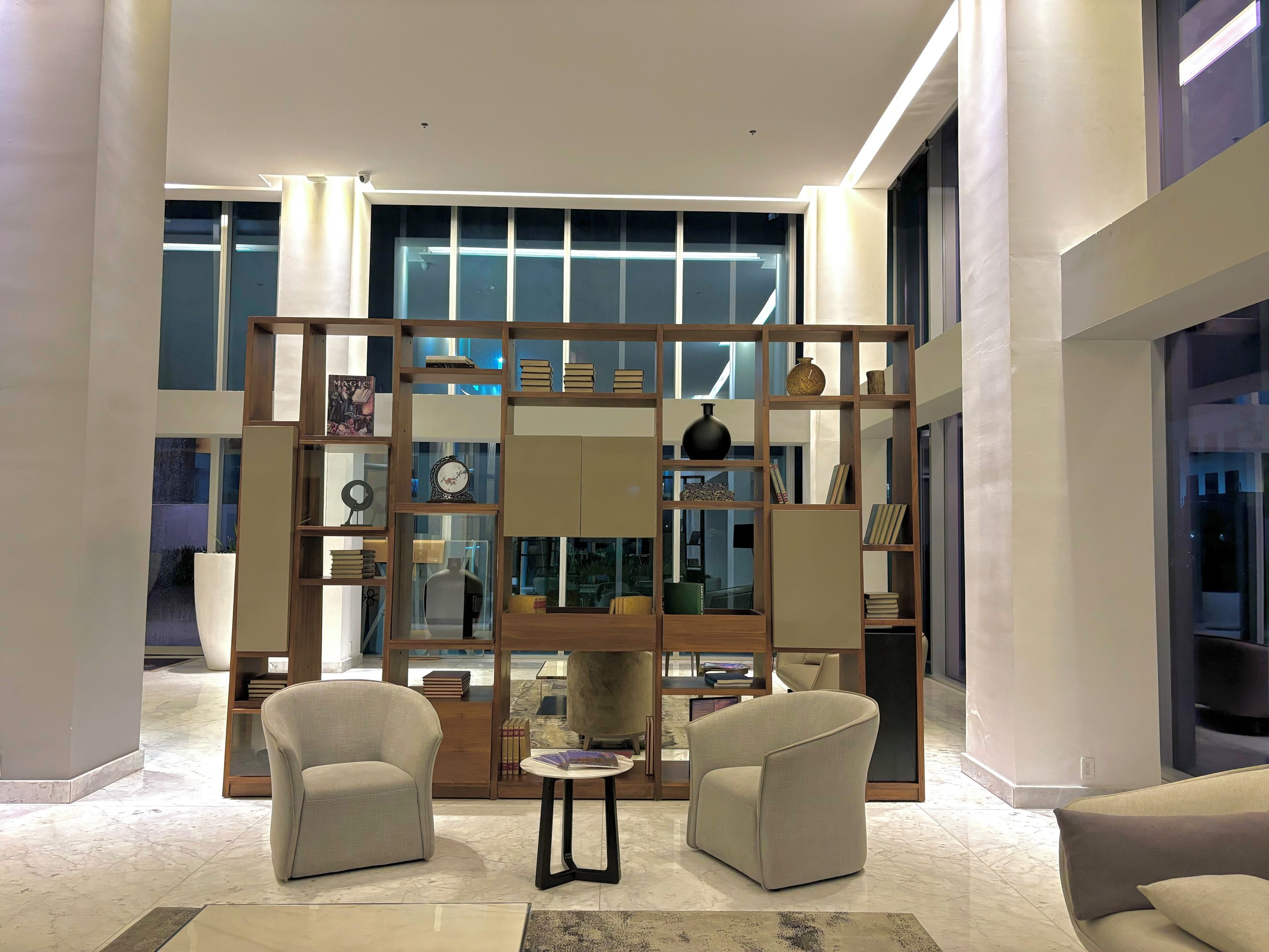 A modern living room with two armchairs, a coffee table, and a decorative wooden partition with shelves.