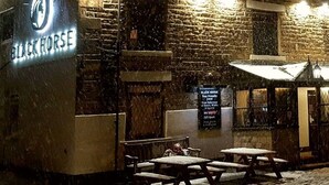 A brick building with a sign reading "BLACK HORSE" and outdoor seating. - The Stables at The Black Horse (Crook)