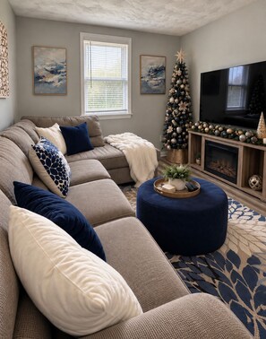Een woonkamer met een hoekbank, een voetenbankje, een open haard en een kerstboom.