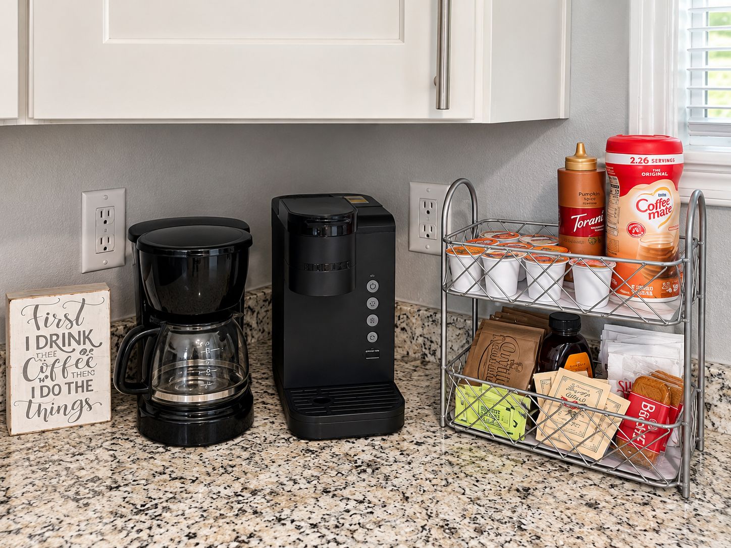 A kitchen with a coffee maker, a coffee machine, and a metal rack holding coffee cups and bags.