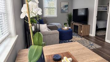 A modern living room with a wooden coffee table, a large white orchid, and a flat-screen TV.