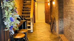 Ein schmaler Korridor mit einer Holztreppe, einem Ventilator und einer dekorativen Blumenkomposition.