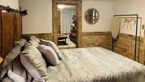 Ein Schlafzimmer mit einem großen Bett, einem Holzkopfstück, einem Spiegel und einem Kleiderständer.