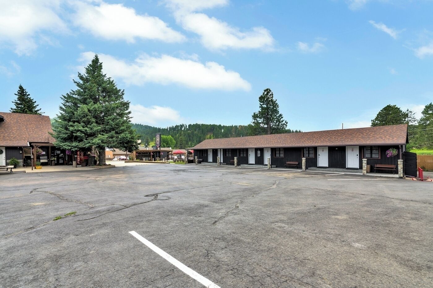 A motel with multiple rooms, a covered parking area, and a large open parking lot.