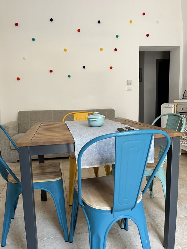 A dining area with a wooden table, blue chairs, and a light blue pot on the table. - ROOF TOP APARTMENT (Palermo)