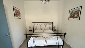 Una camera da letto con un letto, due comodini, un lampadario e due quadri appesi alle pareti.