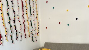 Zona pranzo con tavolo in legno, divano grigio e decorazioni murali colorate.