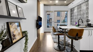 Una cocina moderna con comedor, que cuenta con un amplio ventanal, un televisor de pantalla plana y un detalle decorativo en la pared.