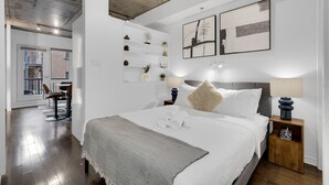 Un dormitorio moderno con una cama grande, mesitas de noche con lámparas, un espejo y una obra de arte en la pared.