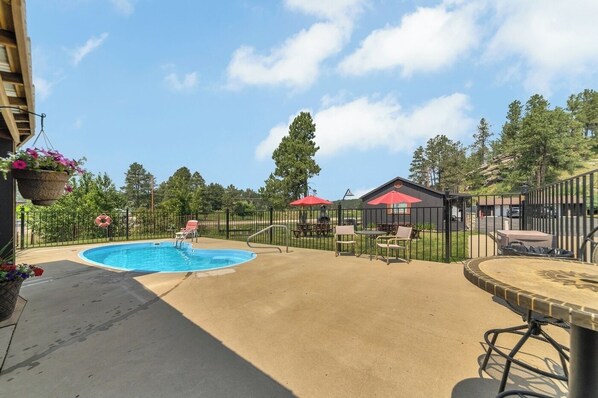 Un jardin avec une piscine, un espace salon extérieur et un coin barbecue.