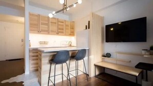 Una cocina moderna con armarios de madera, una isla central con taburetes de bar, un televisor de pantalla plana en la pared y un tapete de cuero de vaca en el suelo.