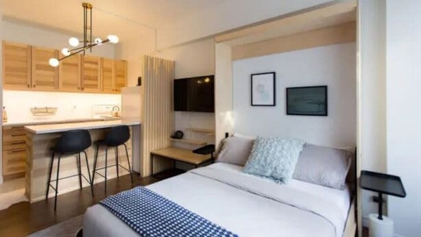 Una habitación de hotel moderna con cama, escritorio y kitchenette.
