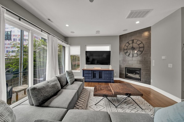 A modern living room with a grey sofa, a coffee table, a TV, and a fireplace.