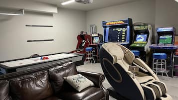 A room with a pool table, massage chair, and several arcade games.