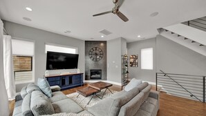 Ein modernes Wohnzimmer mit Flachbildfernseher, Kamin und Treppe.