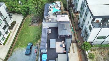 A rooftop patio with outdoor furniture, a pool, and a car parked nearby.