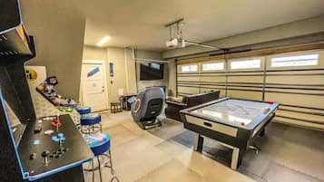 A recreational room with a pool table, a foosball table, and a gaming area.