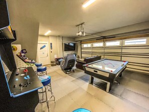 A recreational room with a pool table, a foosball table, and a gaming area.