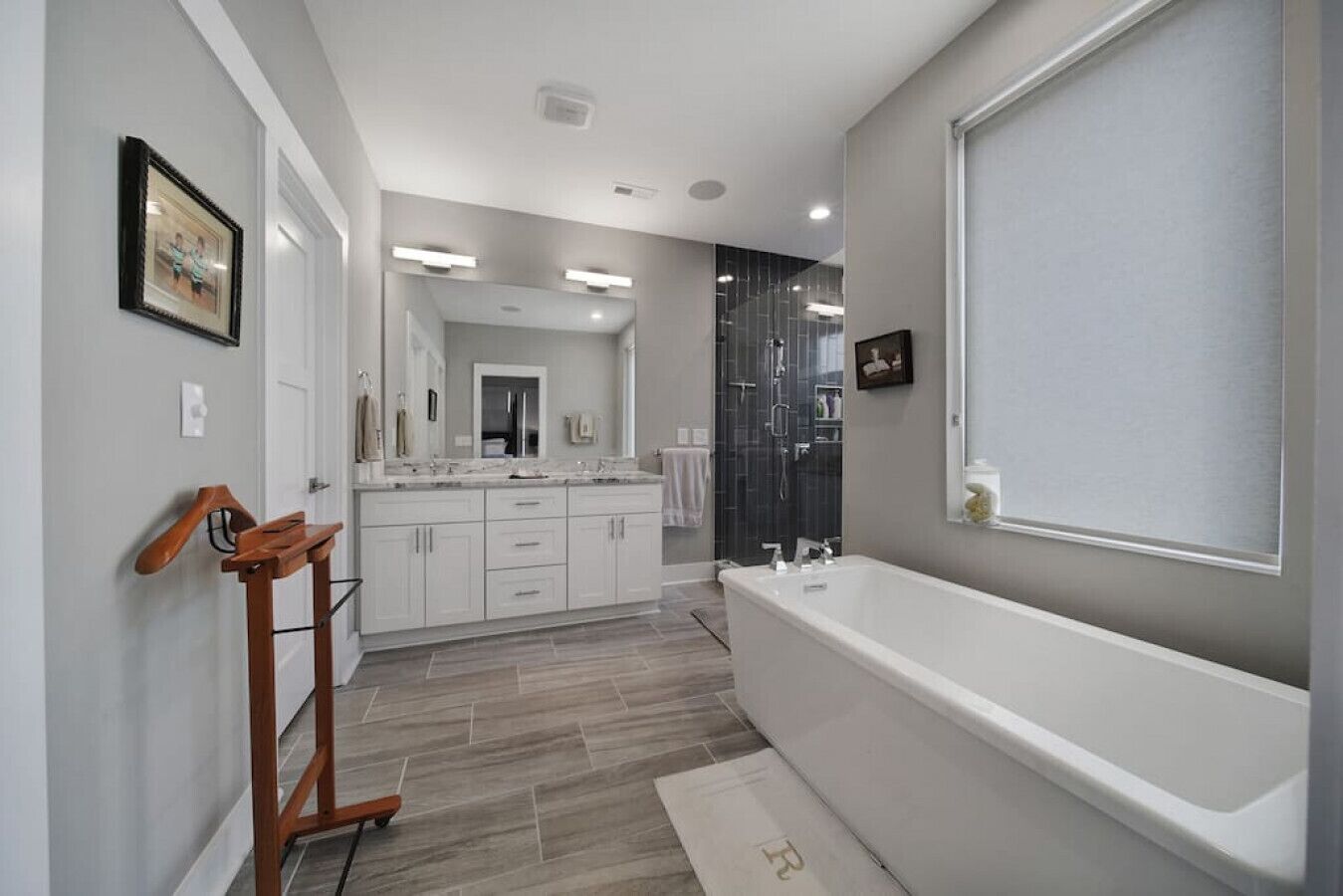 Une salle de bain moderne avec une grande baignoire, un banc en bois et une douche à l’italienne.