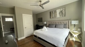 Ein Schlafzimmer mit einem Bett, einem Deckenventilator, einem Schreibtisch und einem Stuhl.