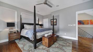 A four-poster bed with a dark finish, a standing lamp, and a patterned rug on a wooden floor.