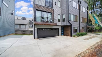 Un immeuble résidentiel moderne à plusieurs étages, doté d’un garage, de grandes fenêtres et d’un porche abrité.