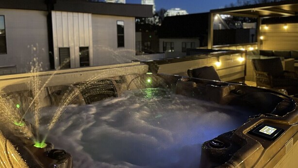 Ein Whirlpool mit digitaler Steuerung, umgeben von Sitzgelegenheiten im Freien.