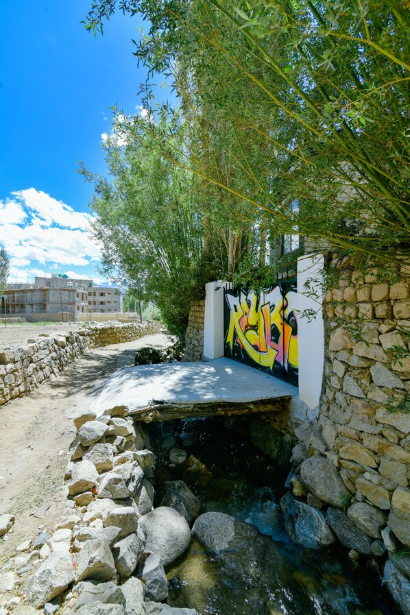 A stone wall with graffiti, a small stream, and a clear blue sky.